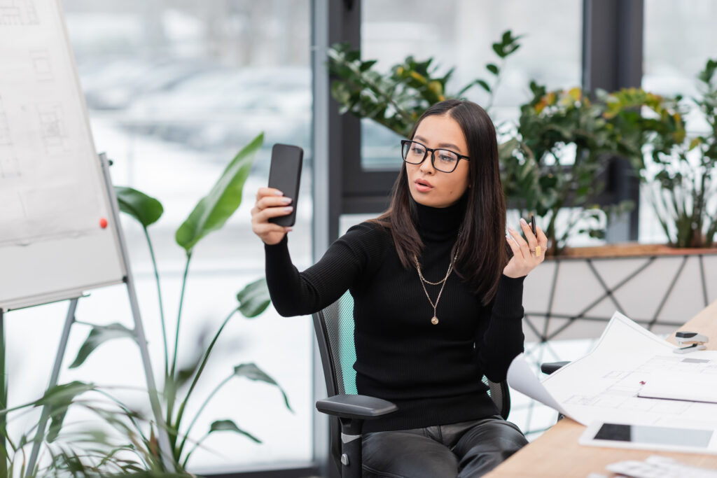 Professional marketer recording a TikTok video in a modern office using a ring light and smartphone.