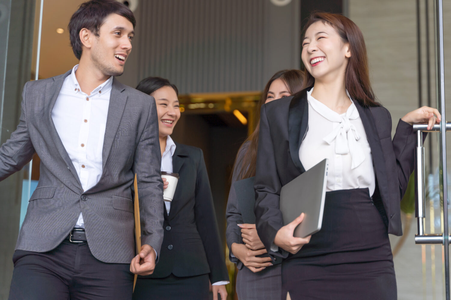 Corporate team in Singapore laughing and high-fiving during an interactive training exercise in a modern meeting room
