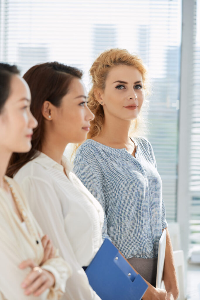 A professional coach leading a group of executives in a modern Singapore conference room, with a city skyline visible through the windows