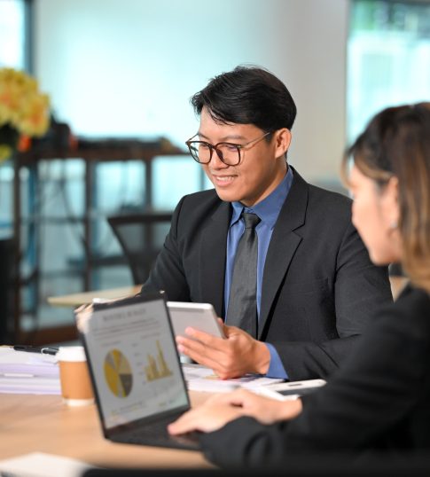 Businessman discussing financial reports with a colleague during a meeting in a modern office.
