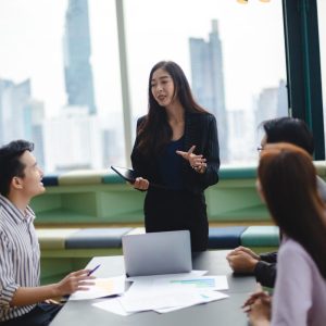 A coach presenting a leadership framework on a whiteboard to a group of attentive executives
